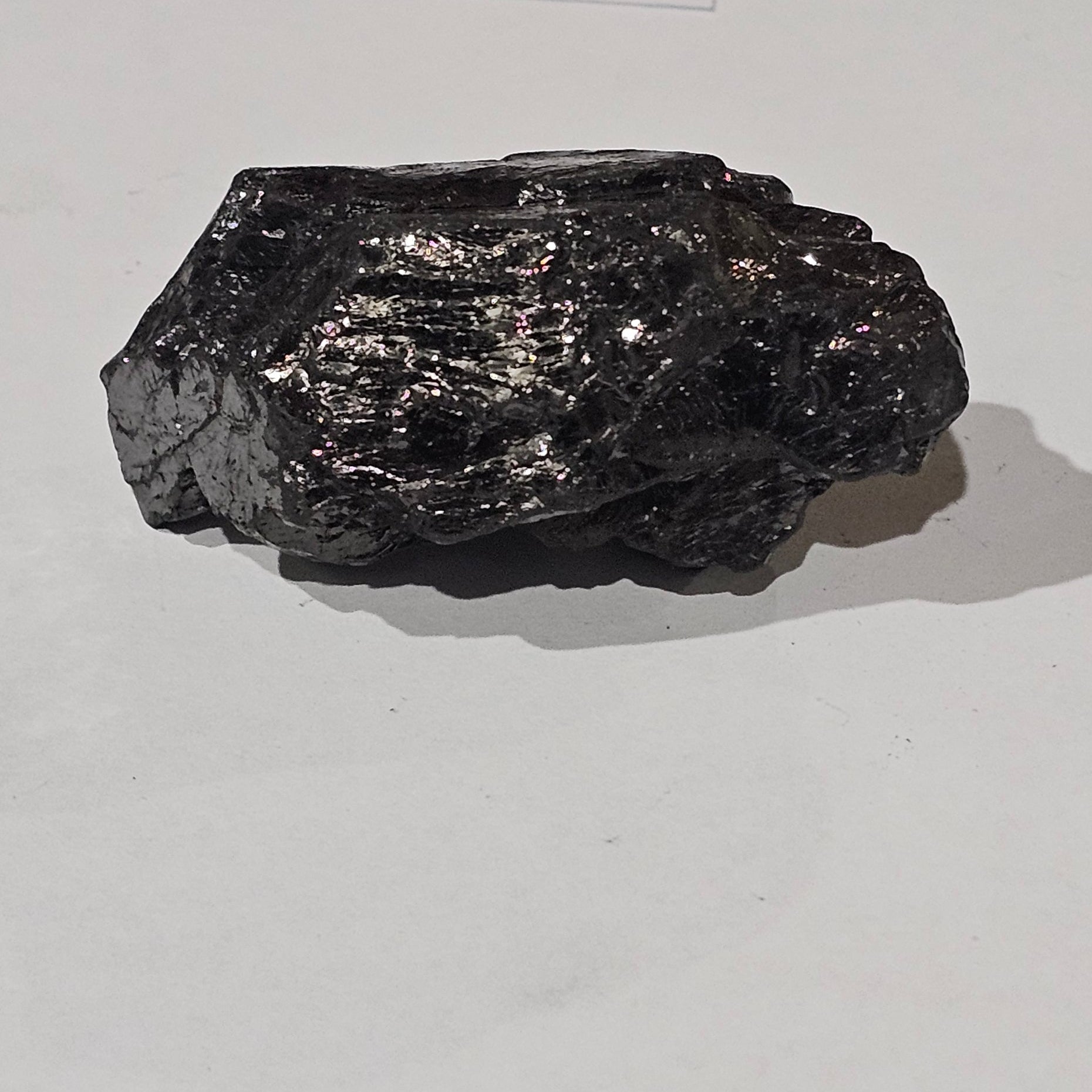 Black mineral sample on a white paper with a wooden surface background