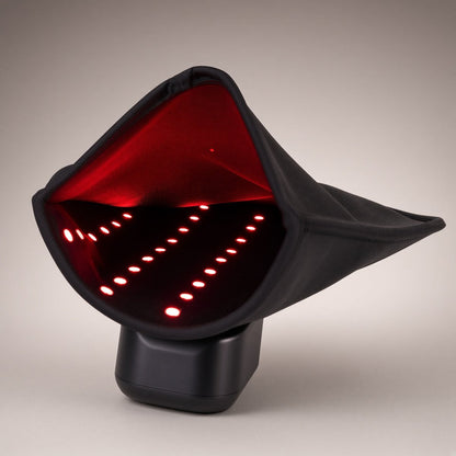 Black hand wrap standing open on its base, rows of glowing red LEDs lining the inside, on grey
