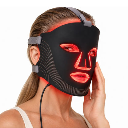 Woman wearing a glowing red light therapy mask NZ with adjustable grey head straps