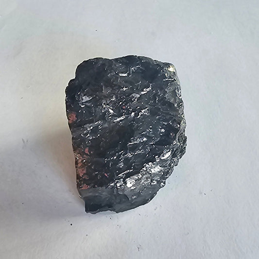 Elite shungite nugget #10, 56.2g: large upright black chunk with silvery flecks, close up on white paper
