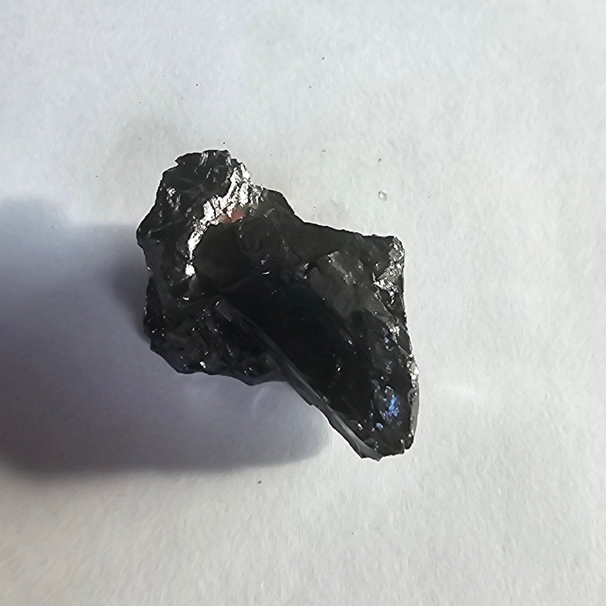 Mount Tasman shungite crystal, 12.3g one-piece nugget: upright nugget with a smooth dark face and a blue-violet glint