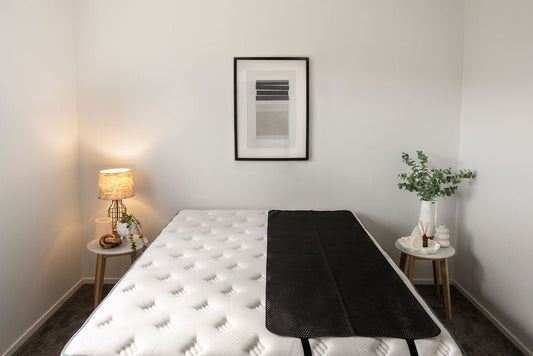 single sized earthing mat laying on a large bed. 